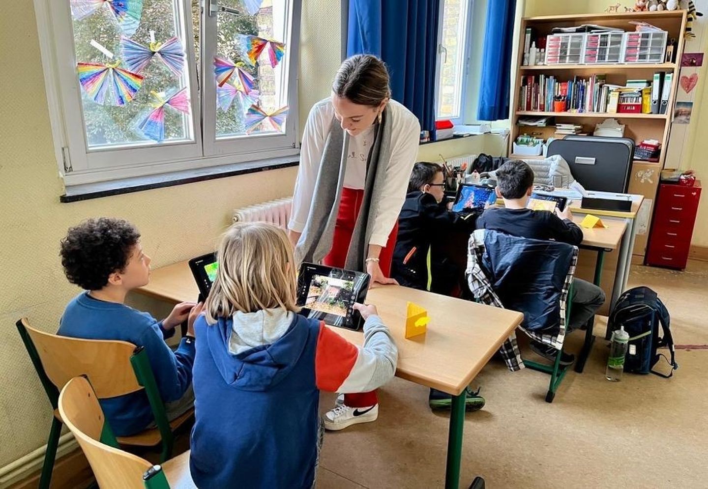 Eine Auszubildende der Stadtwerke Düsseldorf zeigt Schüler:innen der Konkordiaschule etwas am Tablet 