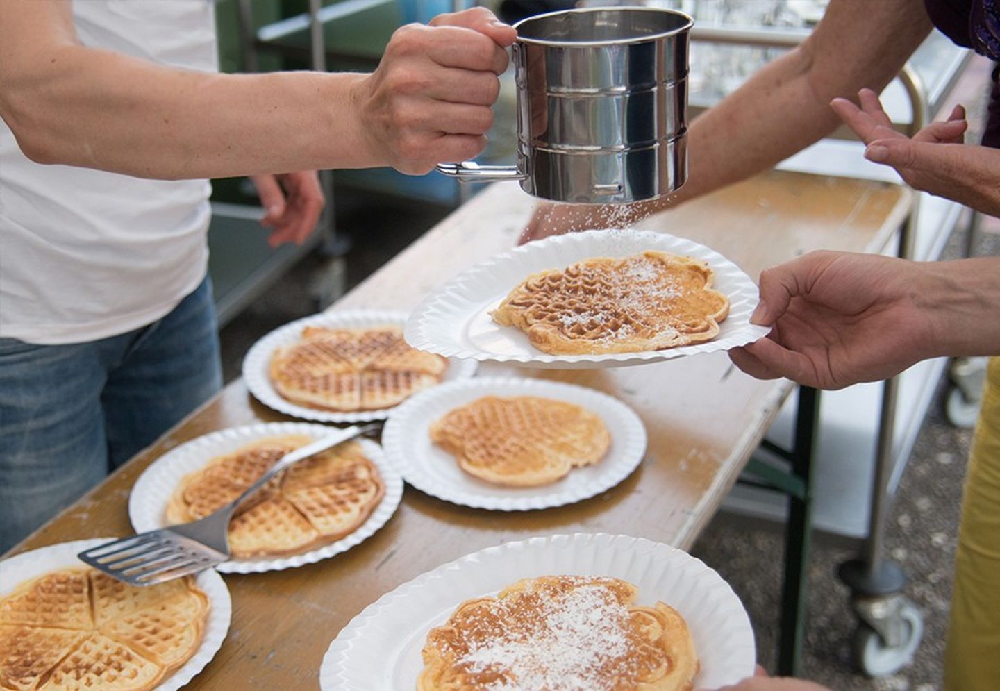 Waffelteller auf einem Tapeziertisch wird mit Puderzucker bestäubt.