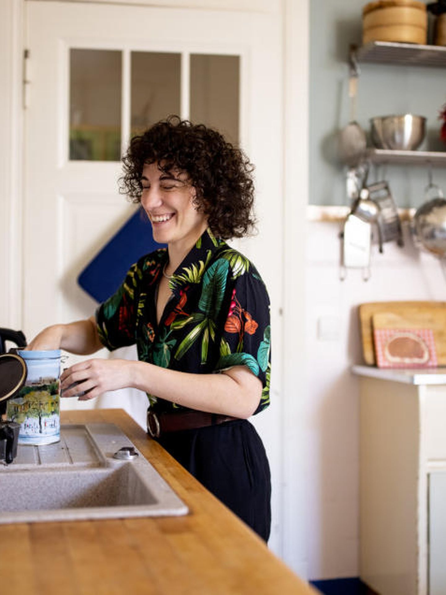 Eine nicht-binäre Person bereitet einen Kaffee in der Küche zu. 