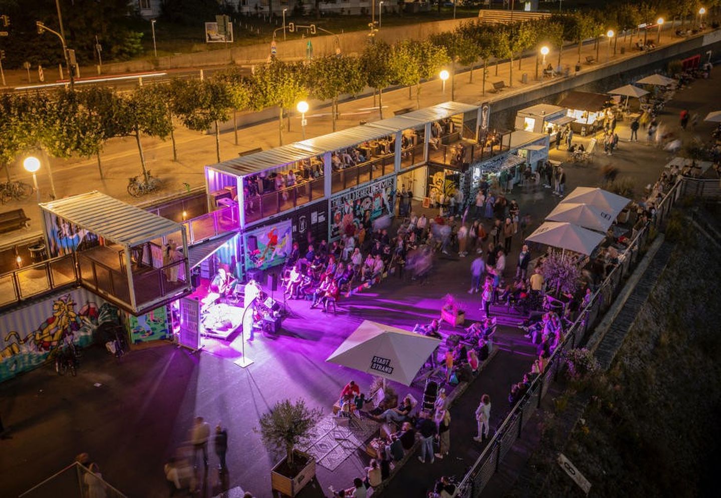 Besucher:innen lauschen einem Konzert am Stadtstrand Düsseldorf. 