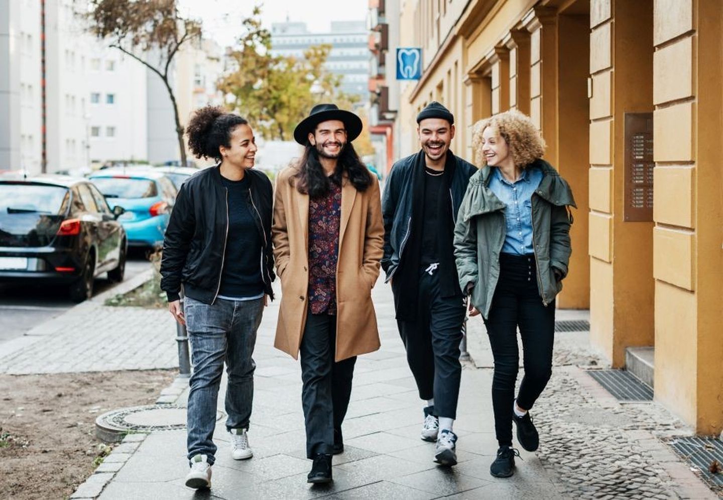 Eine Gruppe von Freund:innen schlendert lachend durch die Stadt.