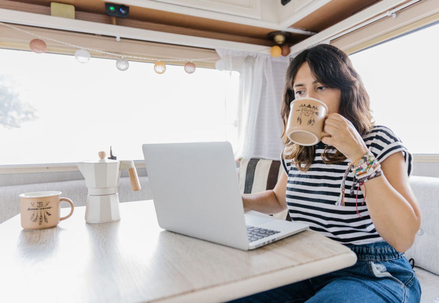 Eine Frau trinkt einen Kaffee vor ihrem Laptop