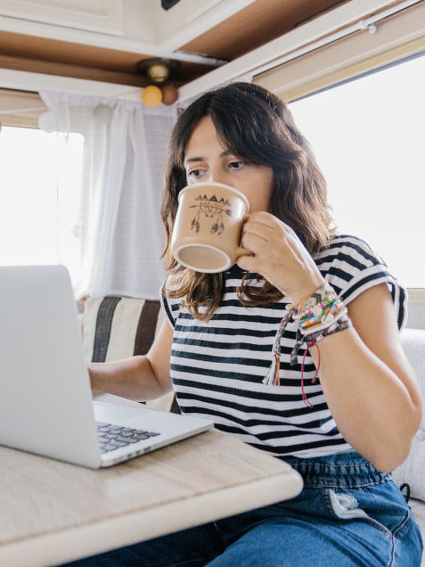 Eine Frau trinkt einen Kaffee vor ihrem Laptop