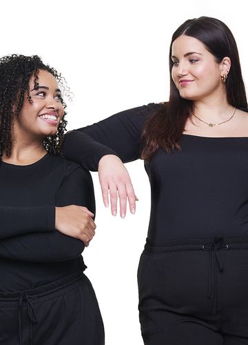Women wearing black smiling at one another