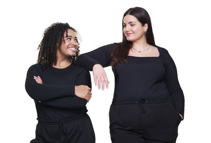 Women wearing black smiling at one another