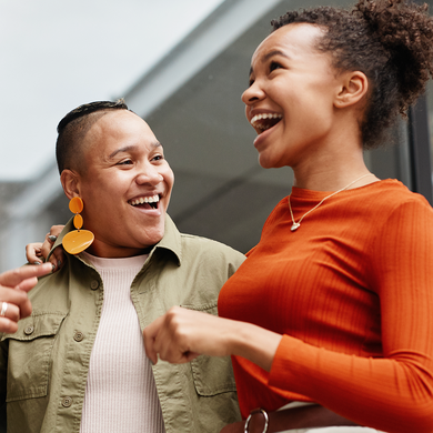 Woman with arm around another woman both laughing