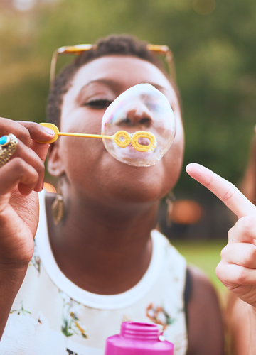 Woman blowing bubbles and another woman pointing at the bubble