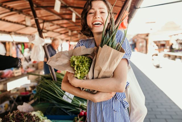 Woman in blue and white striped dress smiling holding vegetables