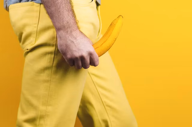 man sporting yellow trousers brandishing a yellow banana