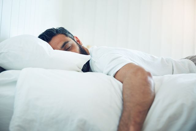 man-asleep-on-white-bed