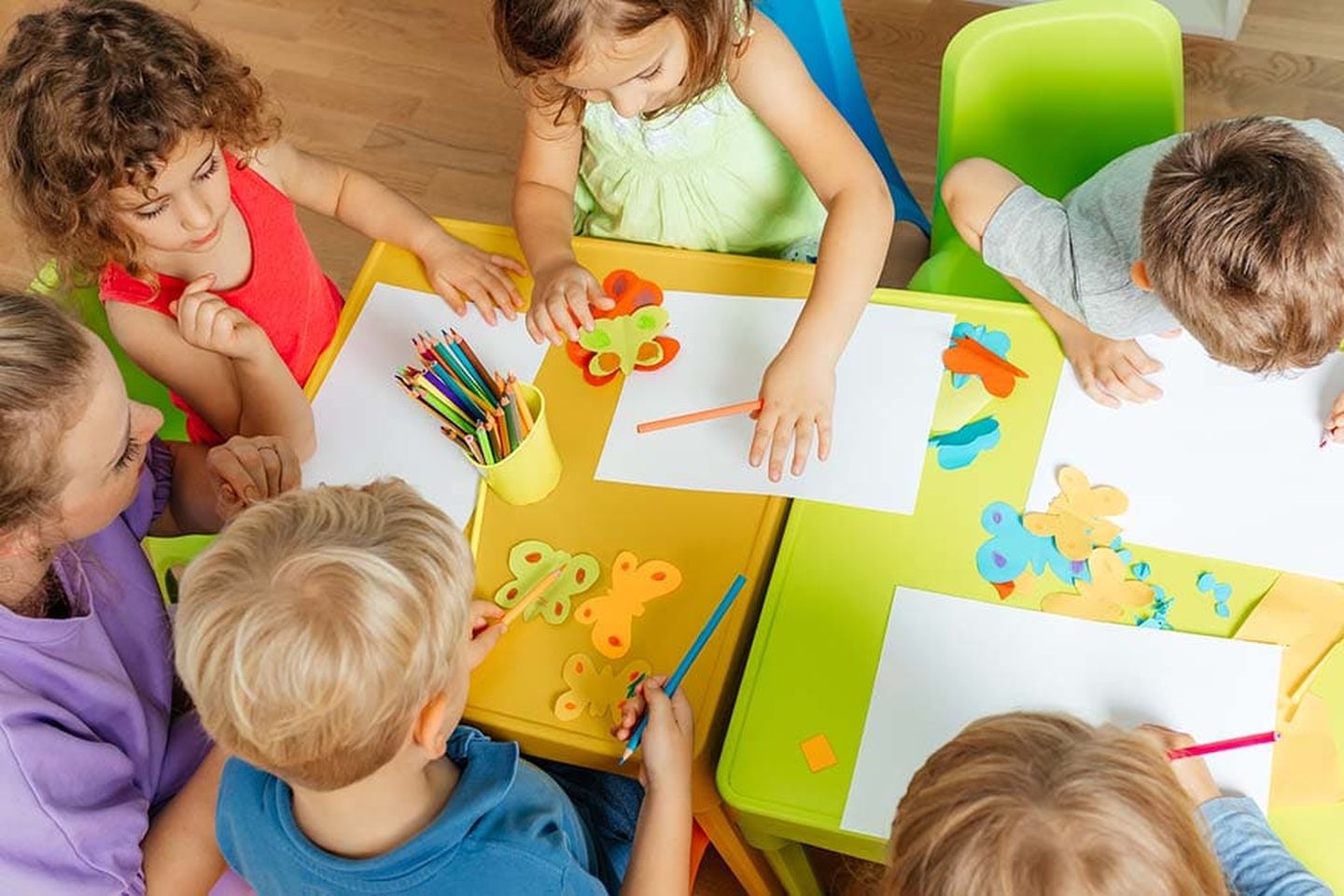 Kinder vor gemalten Bildern an einem bunten Tisch