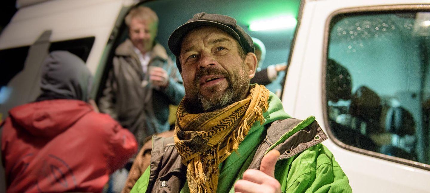 Ein Mann steht vor dem gutenachtbus in Düsseldorf und hält seinen Daumen hoch.