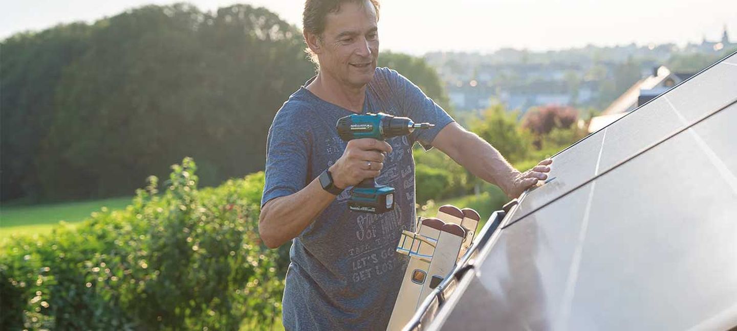 Ein Mann installiert ein Balkonkraftwerk auf einem Schrägdach © solago