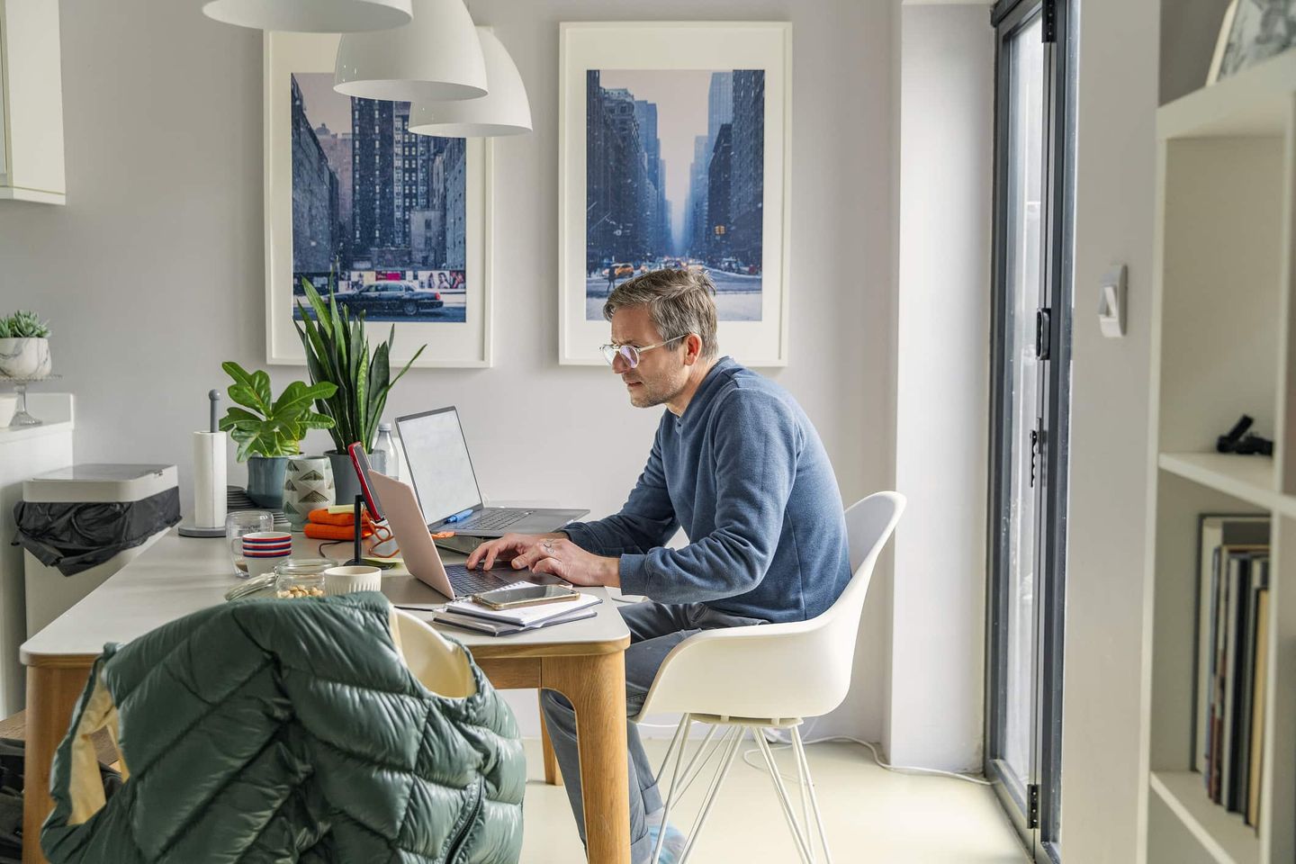 Mann arbeitet im Homeoffice am Laptop in heller Wohnung. Getty