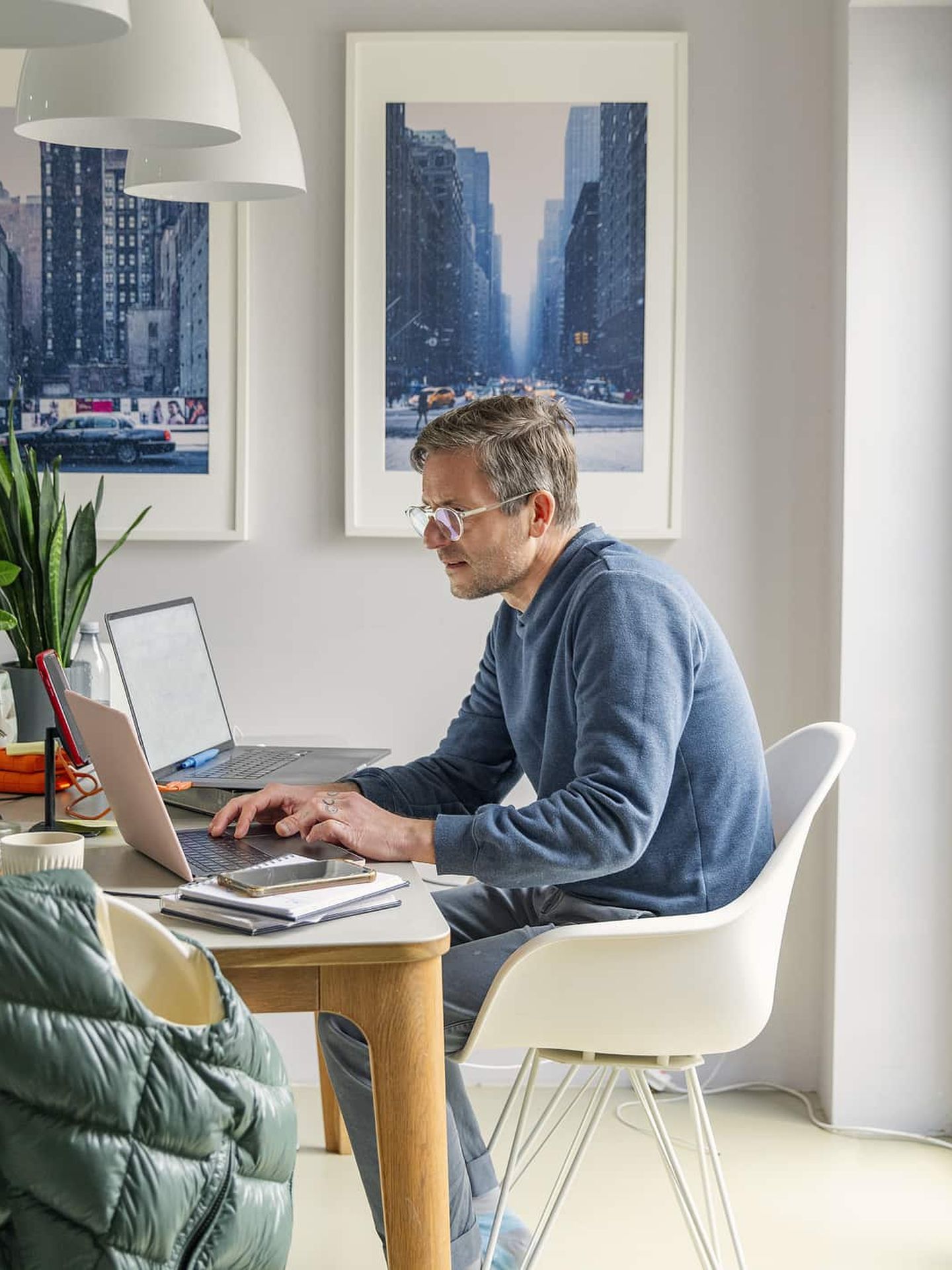 Mann arbeitet im Homeoffice am Laptop in heller Wohnung. Getty