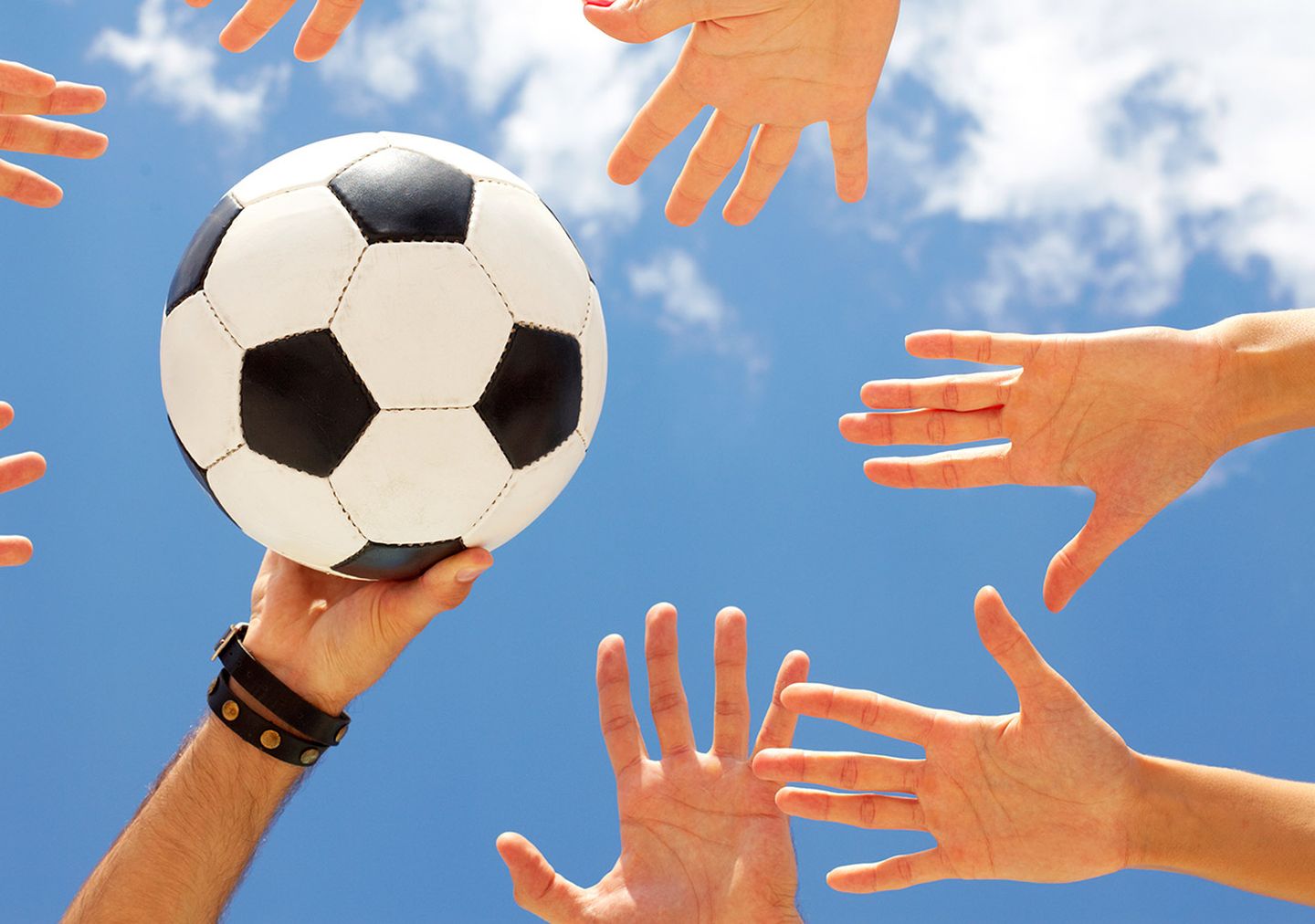 Viele Hände in die Luft gestreckt greifen nach einem Ball