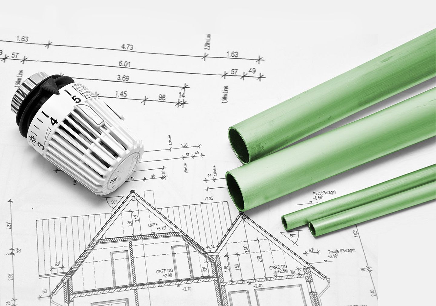 Heizungrohre und Temperaturregler liegen auf den Bauplänen