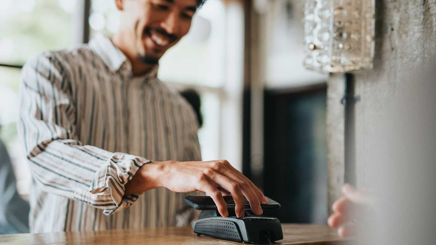 Ein Kunde zahlt in einem Geschäft mit seinem Handy © Maskot / DigitalVision via Getty Images