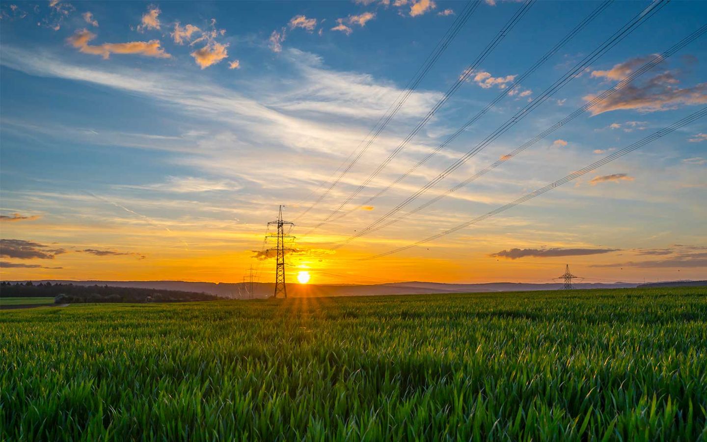 Windkraftanlagen auf einer Wiese bei Sonnenuntergang