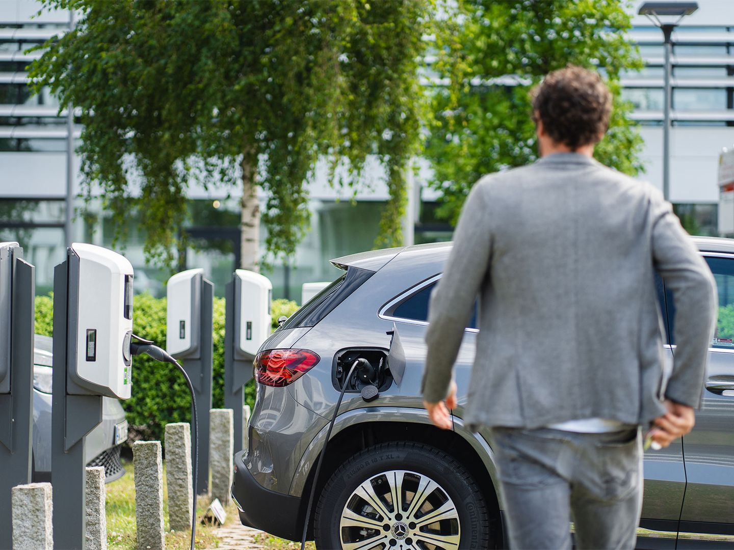 Ein Geschäftsmann kehrt an sein ladendes E-Auto zurück