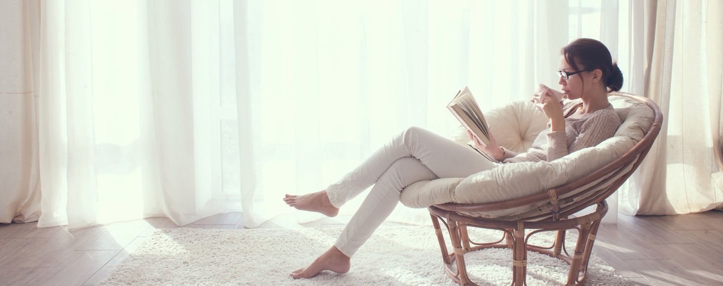 Eine Frau sitzt auf einem Sessel und liest eine Zeitschrift