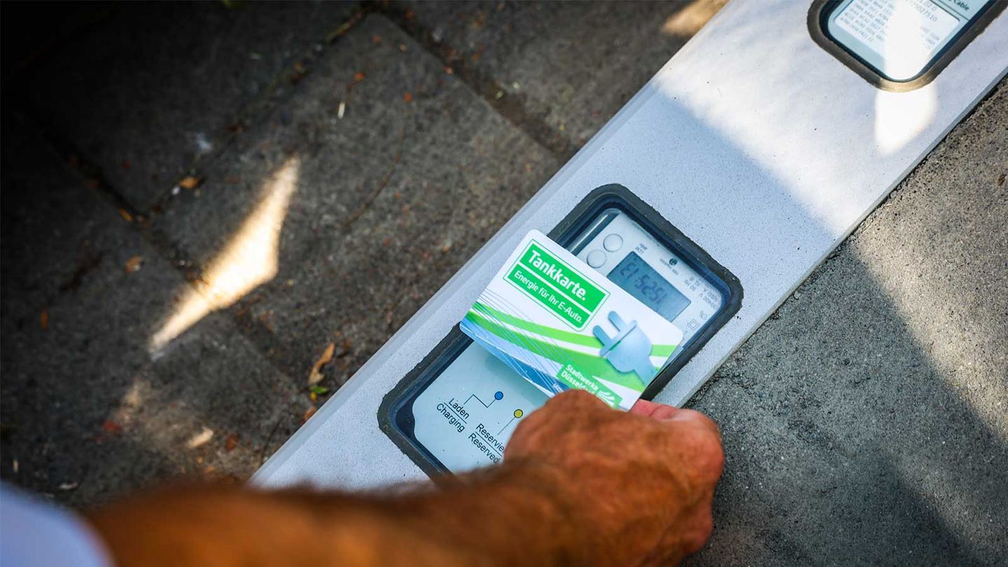 Eine Ladekarte der Stadtwerke Düsseldorf wird an einen Ladebordstein gehalten