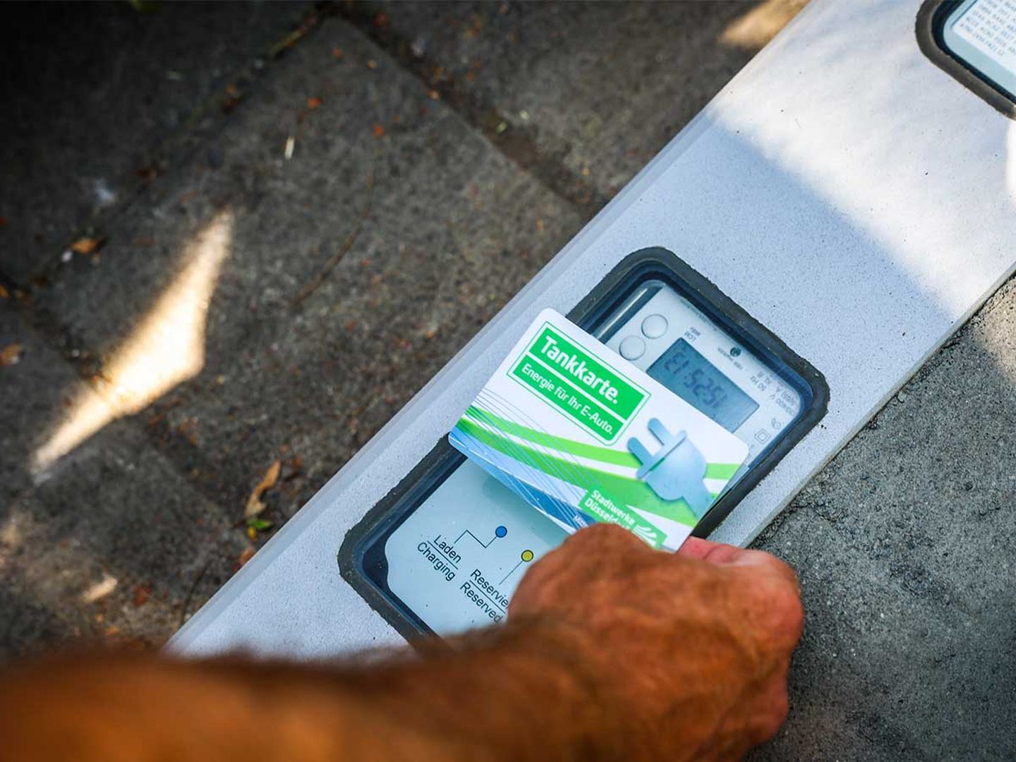 Die Laekarte der Stadtwerke Düsseldorf wird vor den Sensor eines Ladebordsteins gehalten