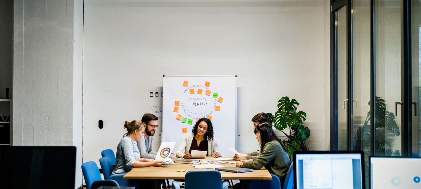 Kolleg:innen sitzen in einem Meetingraum und besprechen ein Projekt