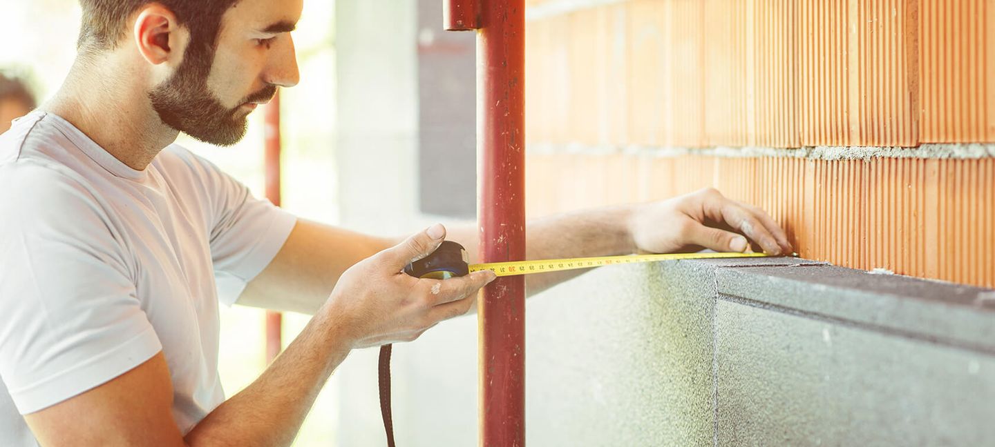 Ein Handwerker auf einer Baustelle mit einem Maßband