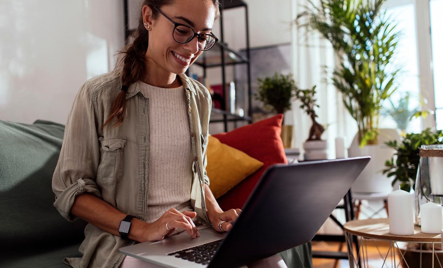 Eine Frau sitzt auf der Couch und meldet Gas online über ihren Laptop an