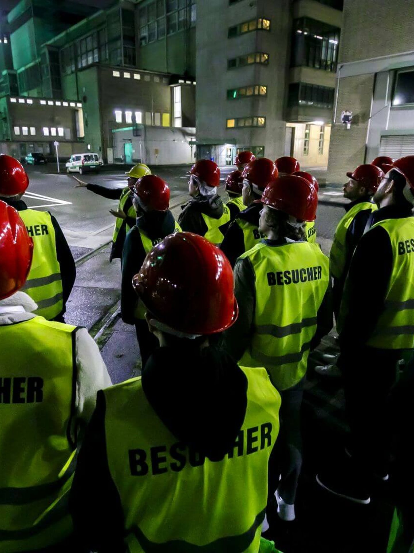 Besucher:innen der Langen Nacht der Industrie stehen als Gruppe samt Warnwesten und Schutzhelmen vor einem Referenten auf Industriegelände. © Stadtwerke Düsseldorf © Stadtwerke Düsseldorf