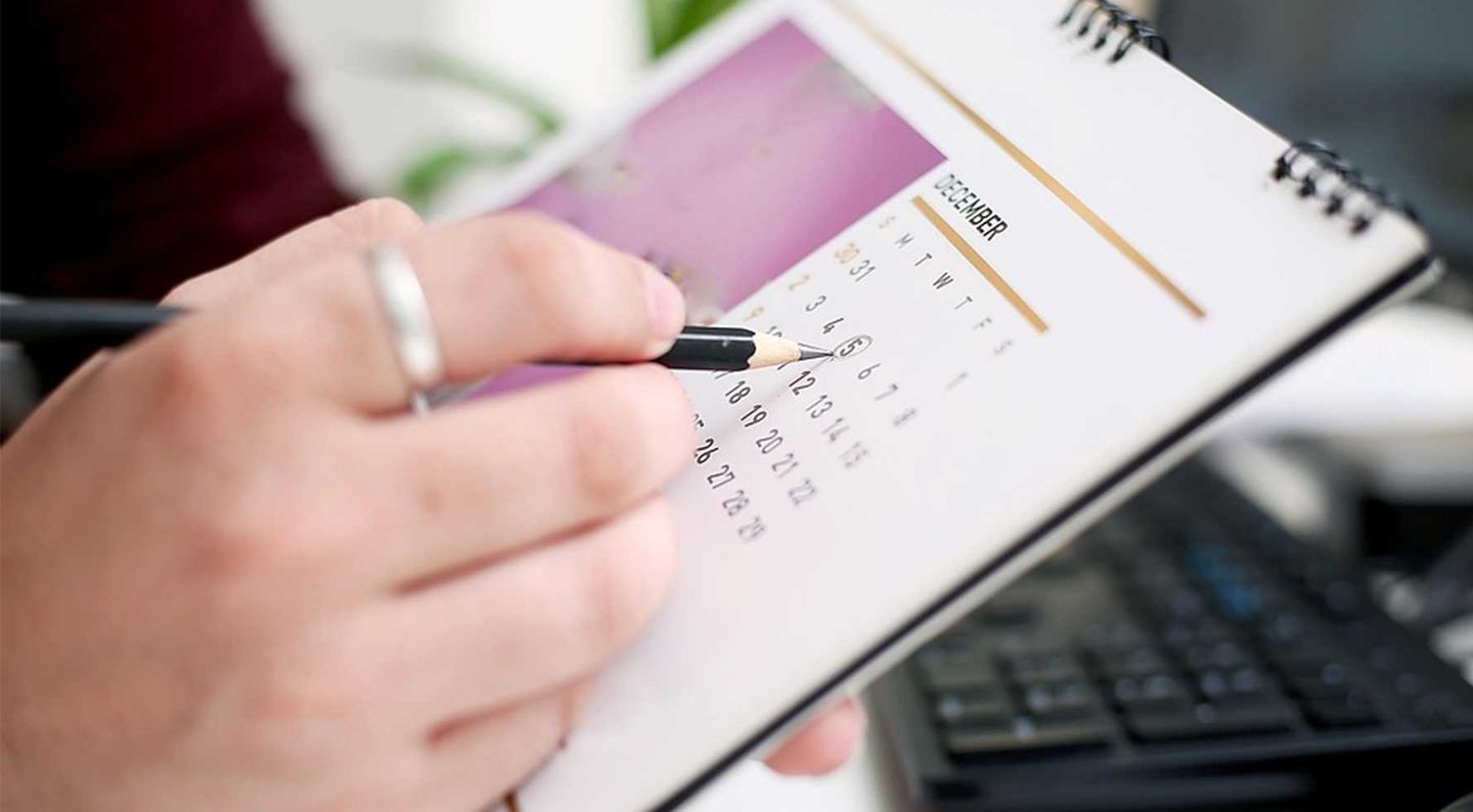 Eine Hand zeichnet etwas in einen Kalender