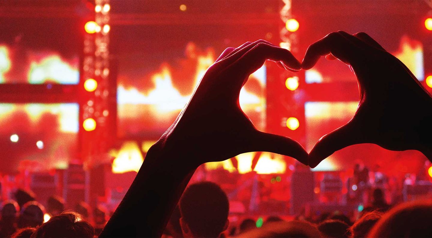 Eine Hand formt ein Herz bei einem Konzert