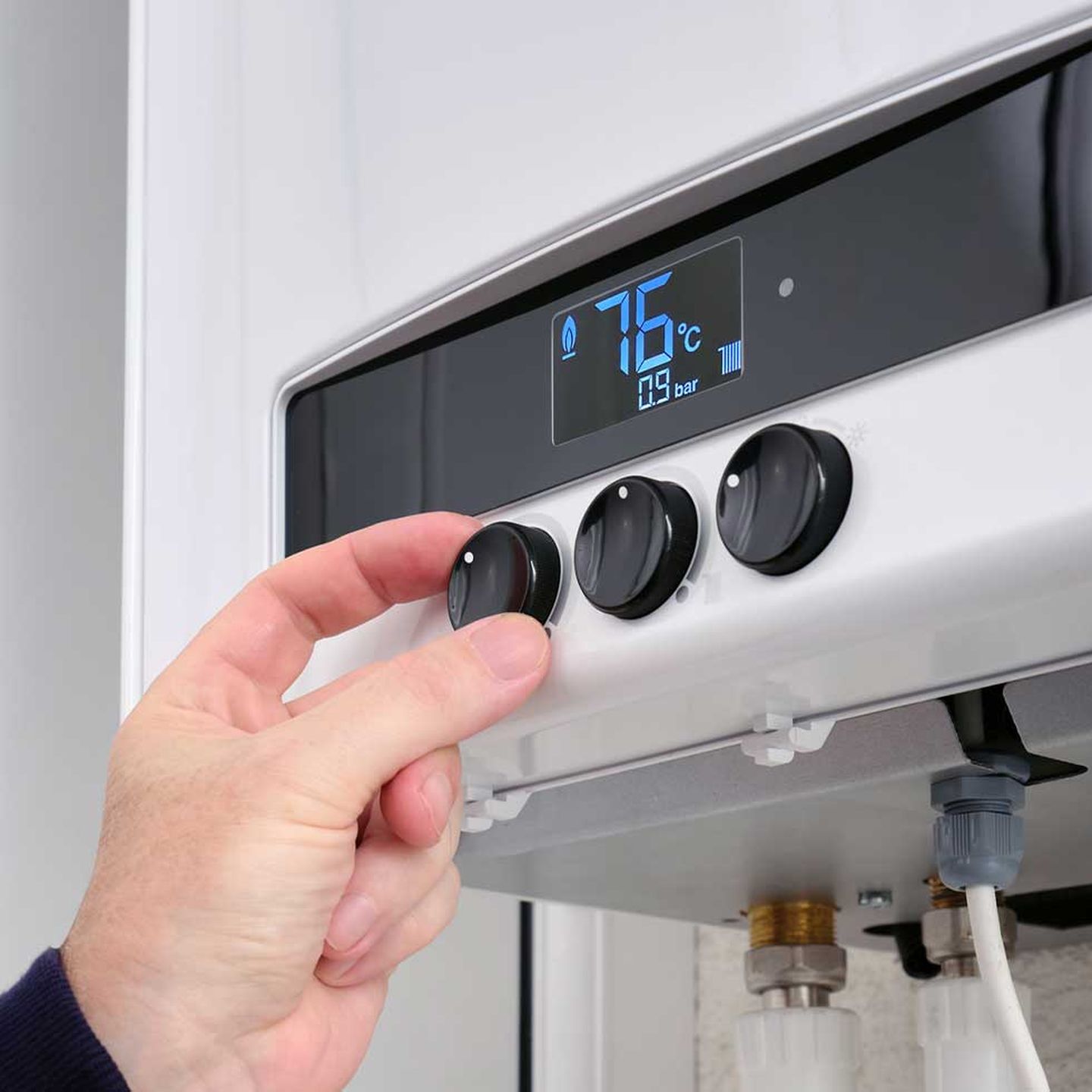 Eine Person stellt die Temperatur ihrer Gasheizung ein. © SergeyKlopotov / iStock/ Getty Images Plus via Getty Images