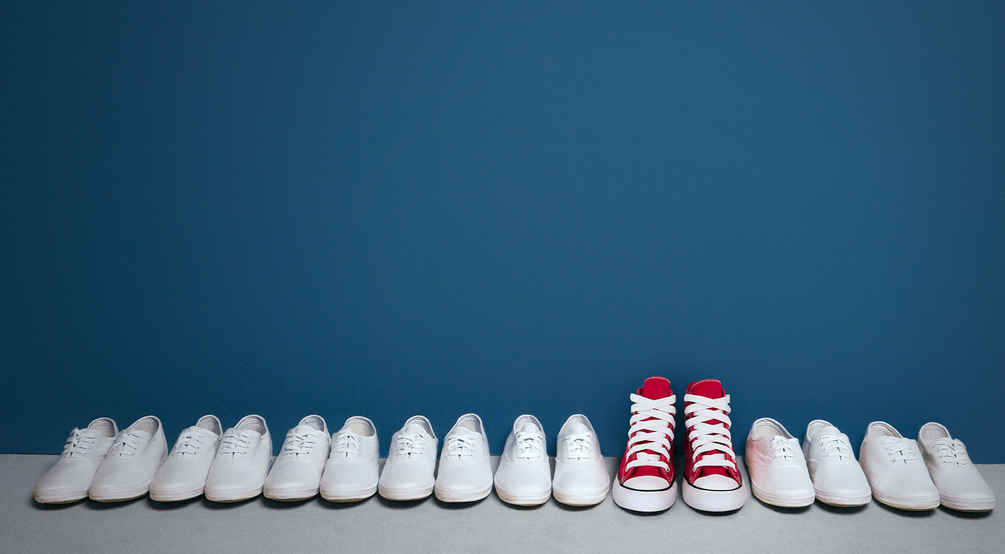 Ein Paar rote Schuhe in einer Reihe von weißen Schuhen