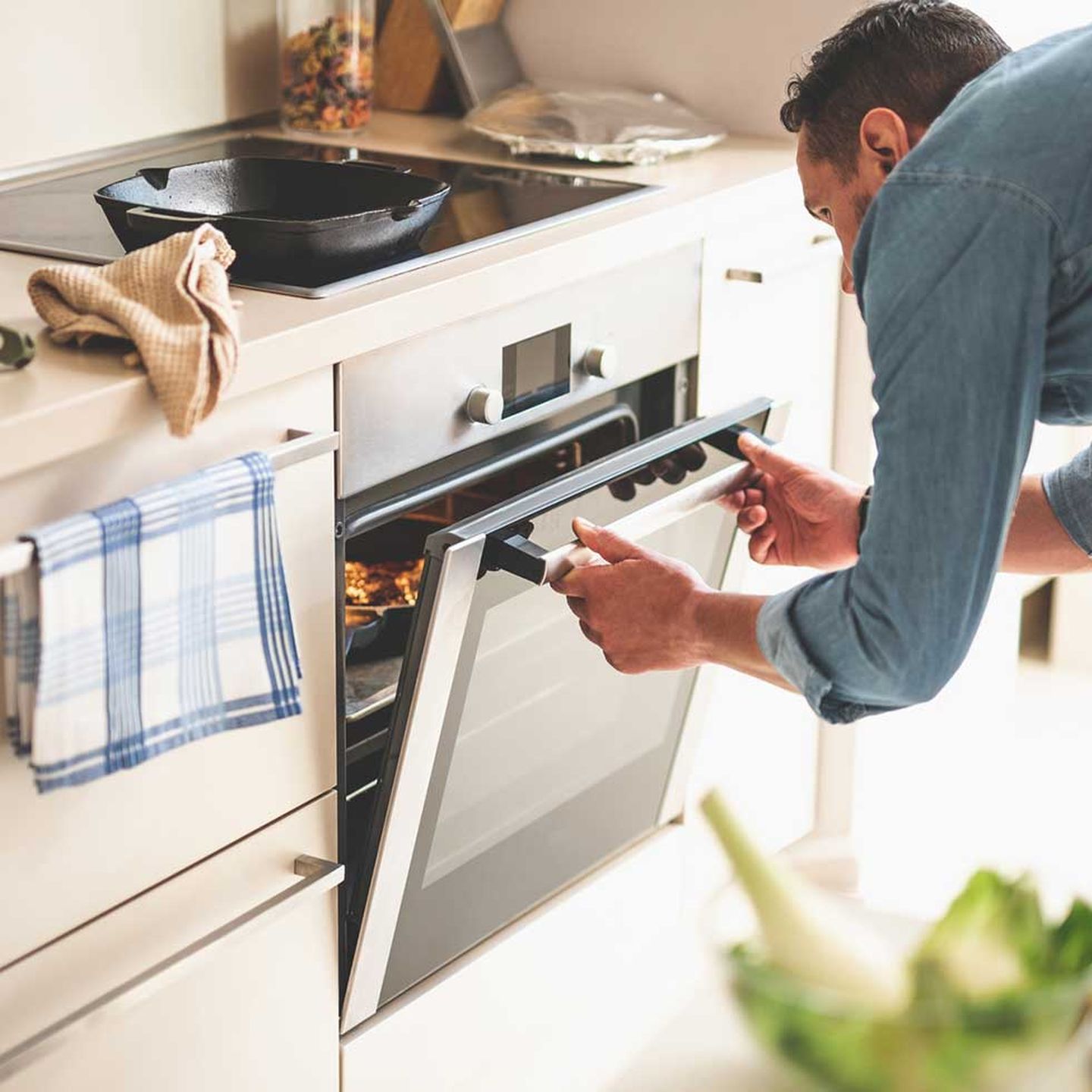 Eine Person steht in der Küche am Herd. Copyright: YakobchukOlena / iStock / Getty Images Plus via Getty Images
