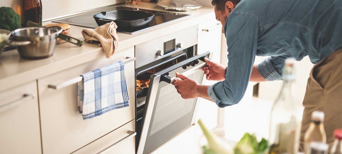 Eine Person steht in der Küche am Herd. Copyright: YakobchukOlena / iStock / Getty Images Plus via Getty Images