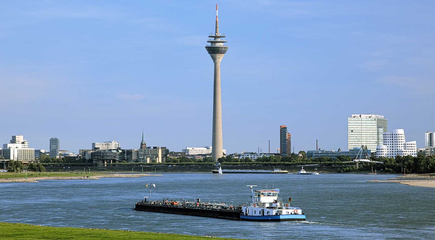 Blick auf den Rheinturm in Düsseldorf mit dem Rhein im Vordergrund © klug-photo via iStock / Getty Images Plus