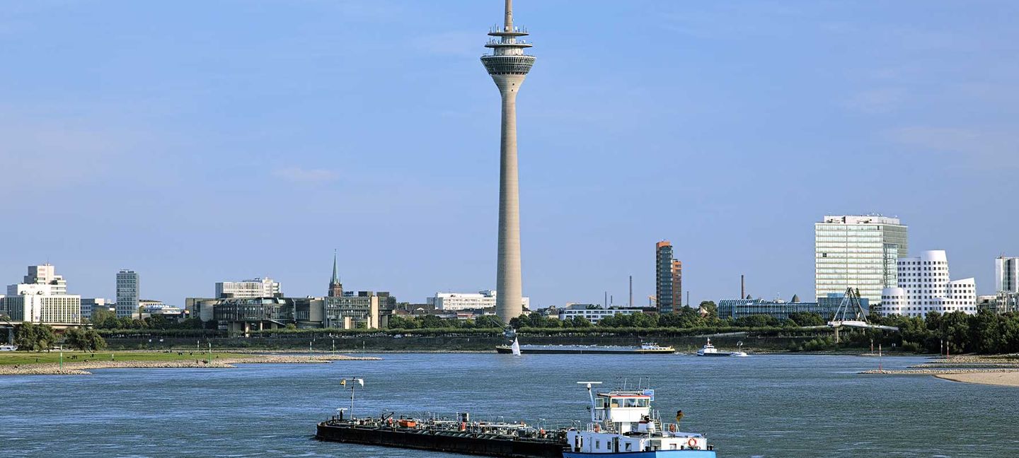 Blick auf den Rheinturm in Düsseldorf mit dem Rhein im Vordergrund © klug-photo via iStock / Getty Images Plus