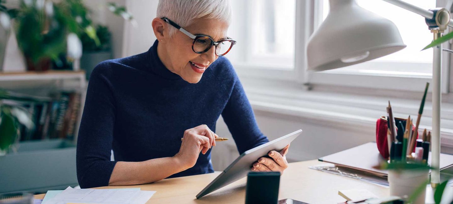 Eine Frau mit kurzen Haaren und Brille an einem Tablet
