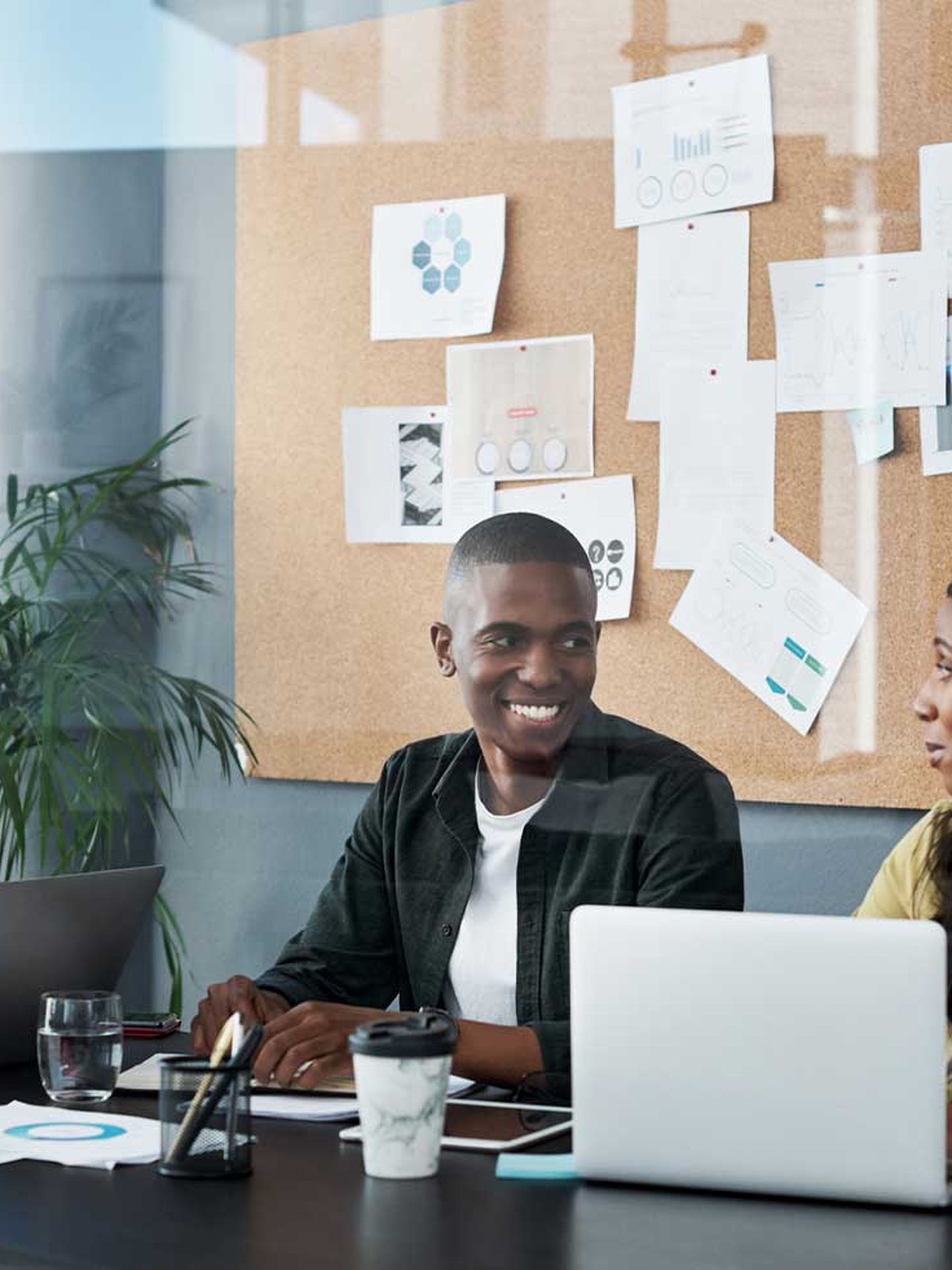 Zwei Frauen und ein Mann unterschiedlicher Generationen sitzen an einem Tisch an ihren Laptops und unterhalten sich. © PeopleImages / iStock / Getty Images Plus via Getty Images