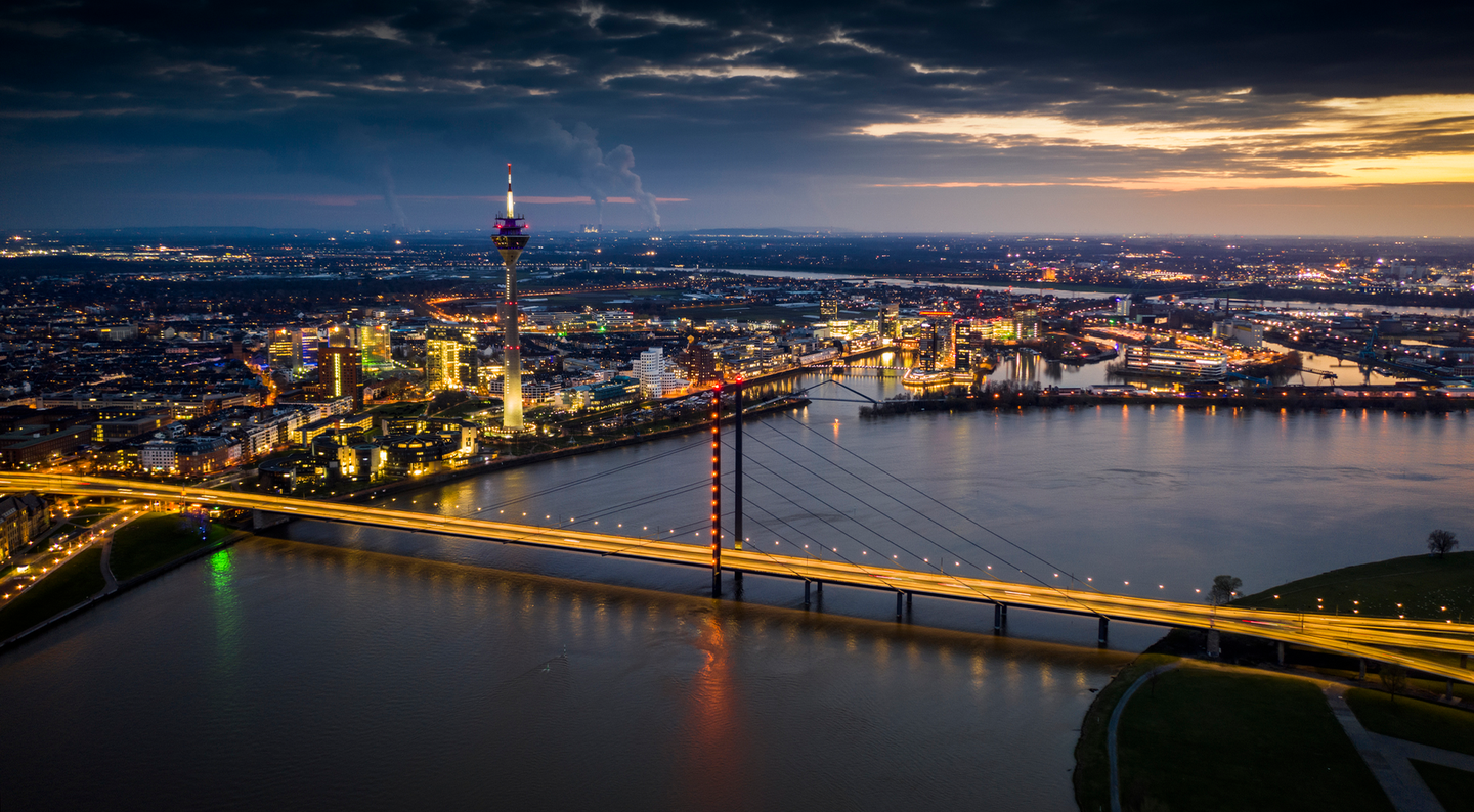 Skyline von Düsseldorf bei Nacht mit beleuchteter Rheinkniebrücke © Schroptschop by Getty Images