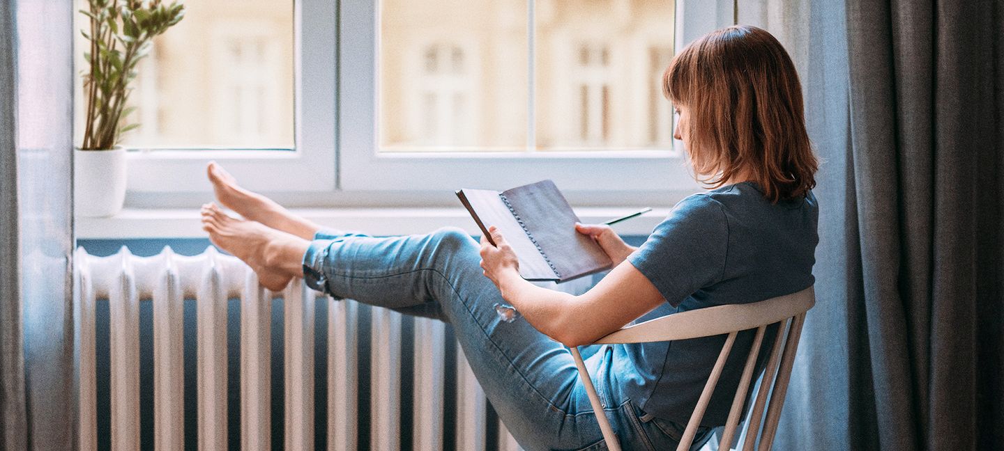 Eine Frau sitzt an einer Heizung