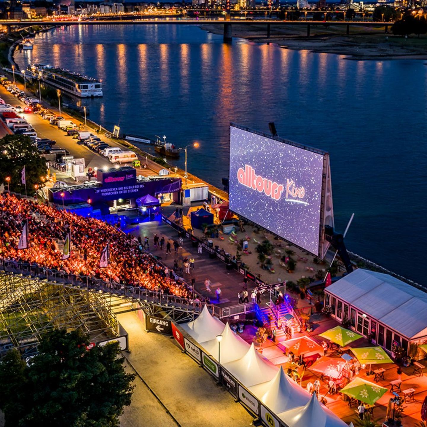 alltours Open-Air-Kino am Düsseldorfer Rheinufer mit großer Leinwand, Publikum und Blick auf den Rhein bei Abendstimmung Kai Kuczera / D.LIVE