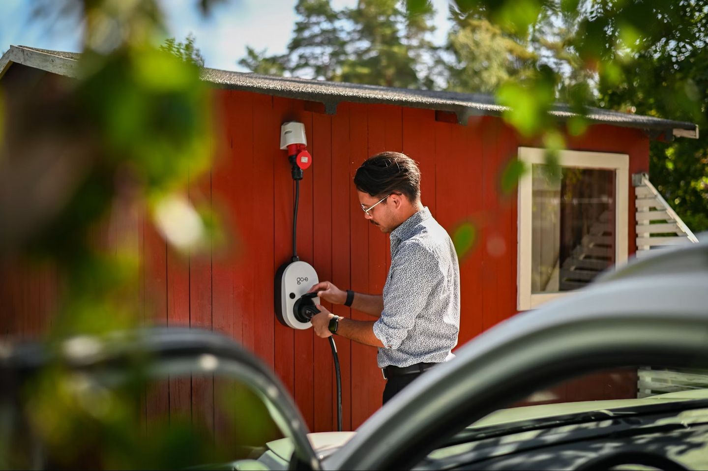 Mann schließt ein Ladegerät für Elektroautos an © Go-e