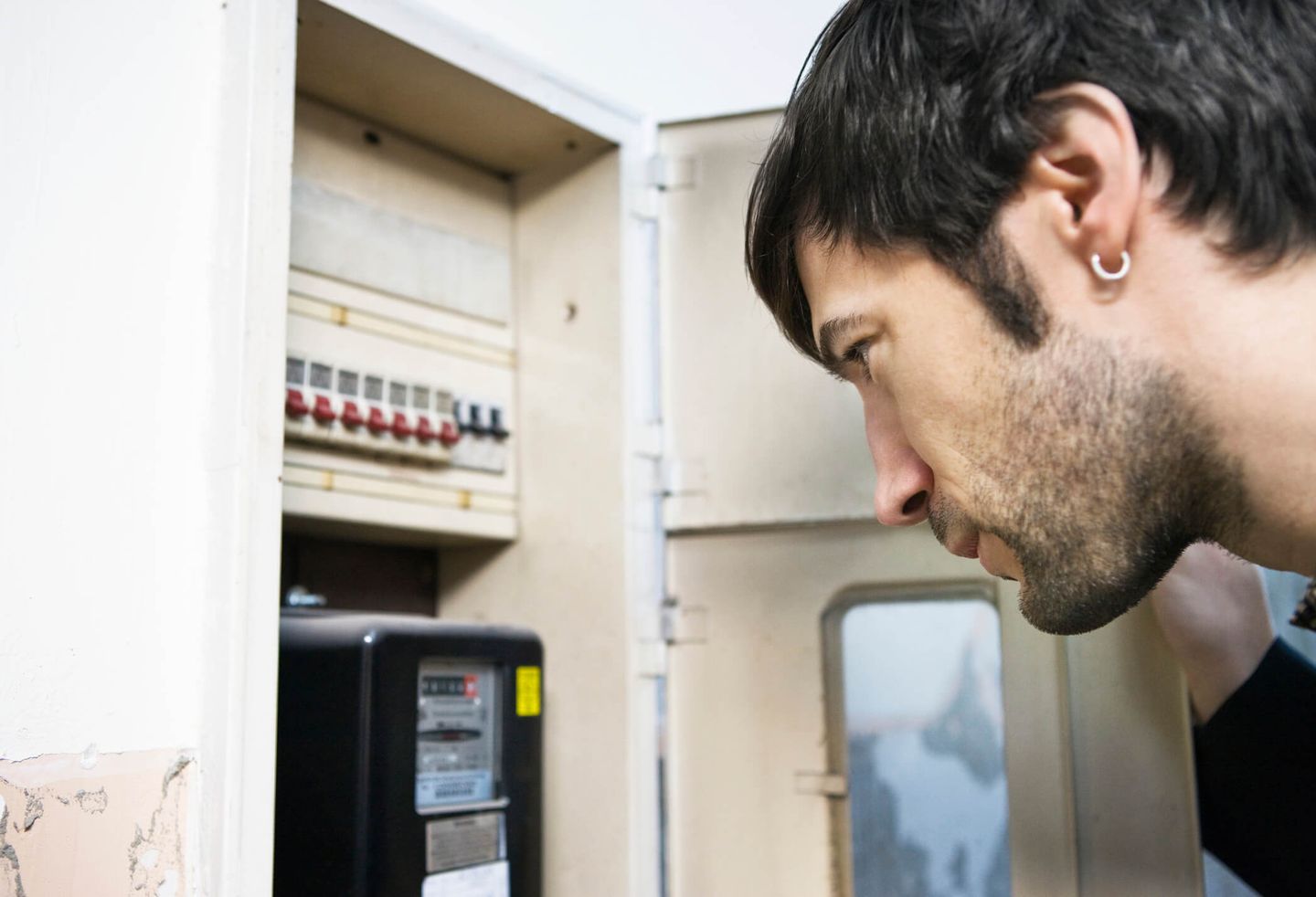 Ein junger Mann liest den Zählerstand in einem Sicherungskasten ab. © Bernd Vogel / Stone via Getty Images © Bernd Vogel / Stone via Getty Images