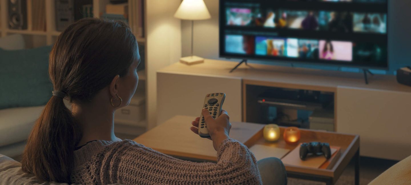 Frau sitzt auf dem Sofa und schaut Fernsehen.© demaerre / iStock / Getty Images Plus