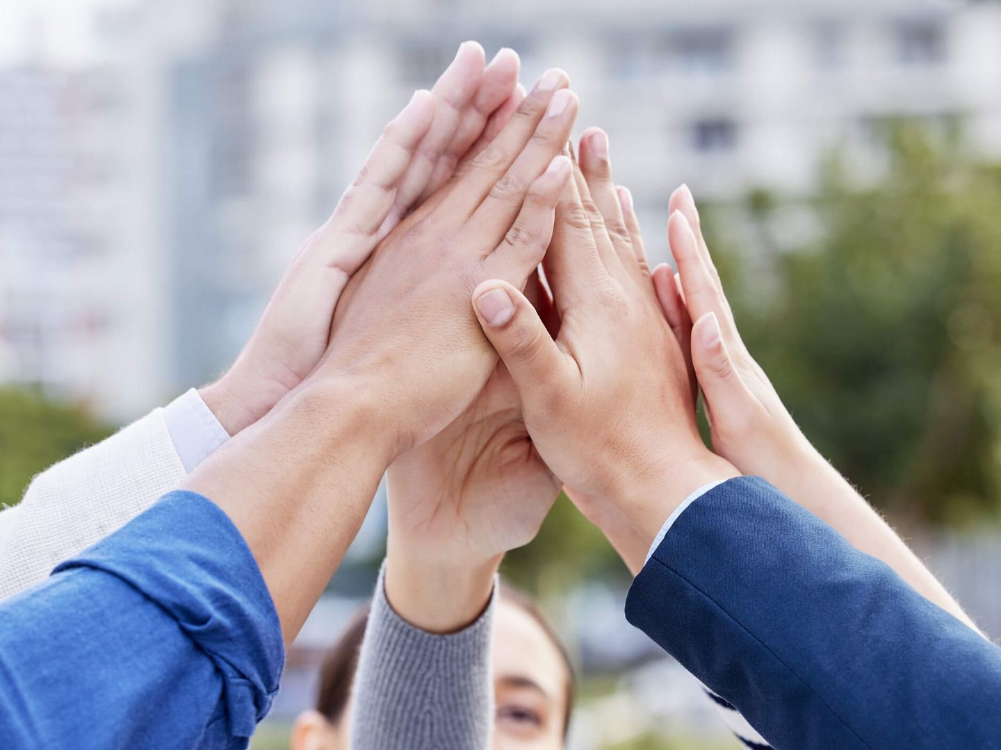 Mehrere Menschen geben sich im Kreis ein High-Five. © PeopleImages / iStock / Getty Images Plus via Getty Images