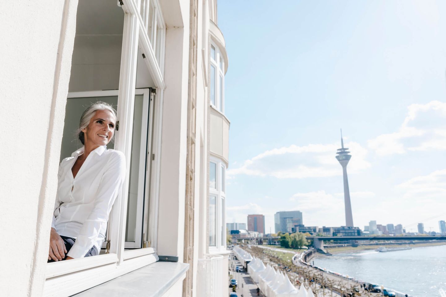 Eine Frau sitzt am offenen Fenster in einer Wohnung in Düsseldorf.