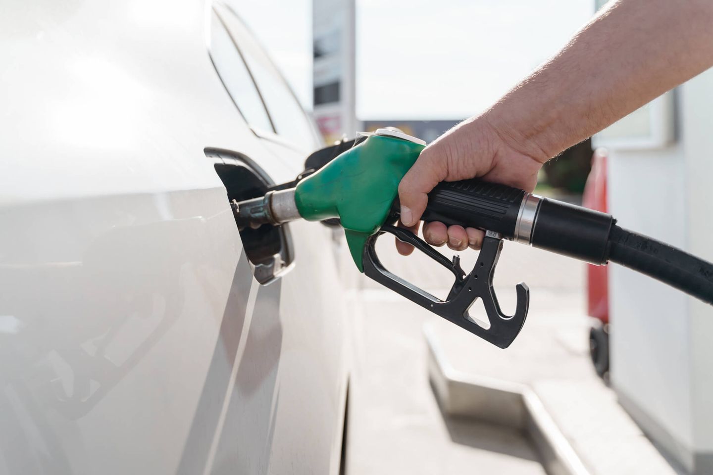 Ein Mann hält einen Zapfhahn an der Tankstelle und betankt sein Auto.  © OLEKSANDRA TROIAN / Moment via Getty Images